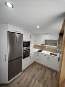 une cuisine avec des armoires blanches et un réfrigérateur en acier inoxydable dans l'établissement A Casa de Salvador - retiro rural con alma gallega, à Vedra 25 autres photos