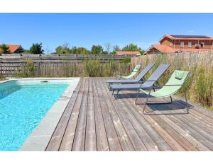 Una terraza con dos sillas y una piscina. en Maison Calme Biscarosse avec Piscine - 10 min Plage, en Biscarrosse