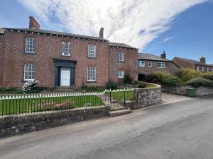 a brick house with a white fence in front of it at Hillside Farm Dormitory - Hikers, Cyclists and Explorers in Carlisle