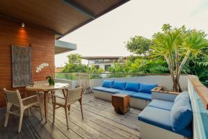 un patio con un sofá azul y una mesa en The Kesari Luxury Villa, en Sanur