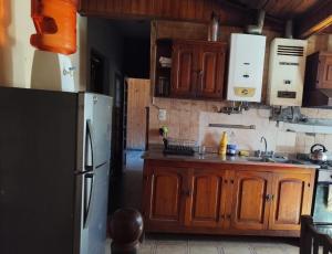Una cocina con gabinetes de madera y refrigerador. en Hostal Orán, en San Ramón de la Nueva Orán