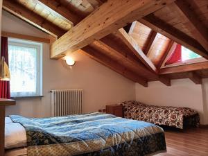 een slaapkamer met een bed in een kamer met houten plafonds bij Appartamenti Villa Maria in Canazei
