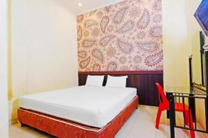 een slaapkamer met een bed en een rode stoel bij Guest House Idola in Palopo