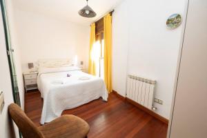 ein Schlafzimmer mit einem weißen Bett und einem Stuhl in der Unterkunft Parque d'Arratiecho l Wifi l Céntrico l Amplio in Biescas