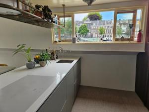 a kitchen with a sink and a window at Woonboot - Houseboat Amsterdam in Amsterdam +12 photos