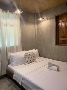 ein Bett mit weißen Laken und Kissen in einem Zimmer in der Unterkunft Goofy Surf House in Burgos