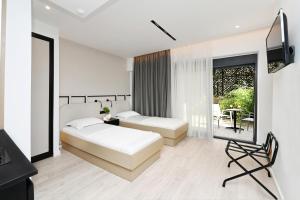 a bedroom with two beds and a television and a balcony at ICON Urban Living in Thessaloniki