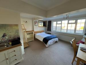 a bedroom with a bed and a desk and windows at The Bunting in Longfield