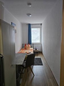 a bedroom with a bed and a table and a window at Monteurs- & Gästewohnungen nähe Raffinerie Leuna & Geiseltalsee für 4Personen in Frankleben