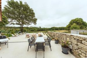 a patio with tables and chairs and a stone wall at Reverence Villas Avieira in Carballal