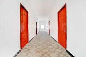 an empty corridor with wooden doors and a tile floor at Collection O Neelambur Near PSG ITech in Irugūr