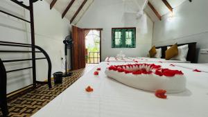 a bedroom with a large bed with red flowers on it at Kurulu Kele Family Tree House in Sigiriya