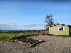 a garden in front of a small green building at Caherhurley Cabin in Tuamgraney