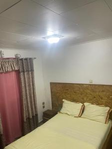Un dormitorio con una cama y una cortina roja. en BML Host, en Douala