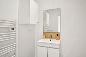 Una cocina blanca con fregadero y refrigerador. en " La Casa verde " Superbe T3, chic & cosy avec climatisation en hypercentre, en Villeurbanne