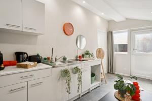 Una cocina con gabinetes blancos y un fregadero. en " La Casa verde " Superbe T3, chic & cosy avec climatisation en hypercentre, en Villeurbanne