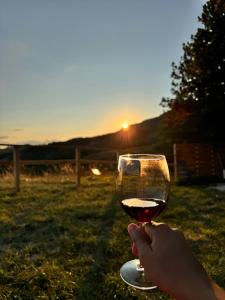 a person holding a glass of wine at sunset at Bubble Room Experience in Casteldelci +48 photos