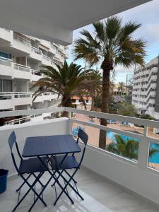 a table and chairs on a balcony with palm trees at Ocean Glimpse- Las Americas in Costa de Adeje