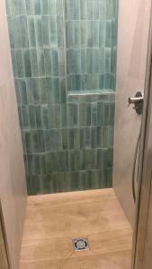 a shower with a green tiled wall and a floor at Lara Elite in Castiglione della Pescaia