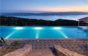 a blue swimming pool with a chair and an umbrella at Holiday home - Apartments Marinjo in Stinica