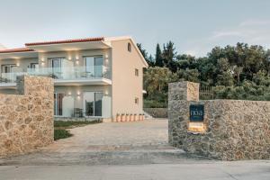 a house with a stone wall in front of it at Noa Suites in Arillas