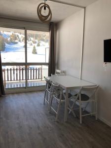 Una mesa y sillas en una habitación con una ventana grande. en Studio Côté Sud, en Superdevoluy