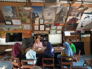 a group of people sitting at a table in a restaurant at Raya Homestay Rammang Rammang in Kasijala