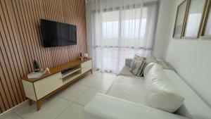 a living room with a white couch and a flat screen tv at TULUM Bertioga - belo apartamento com vista para o mar in Bertioga