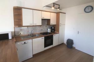 cocina con armarios blancos, fregadero y reloj en Wijk de Brabander 97, en Cadzand