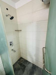 a bathroom with a shower with white tiles at The Dream Stay in Varanasi