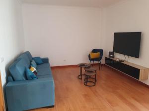 a living room with a blue couch and a tv at O AL da Baixa in Figueira da Foz