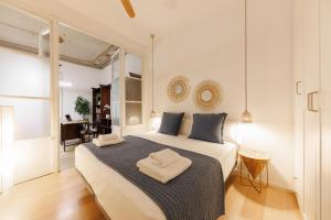 a bedroom with a large white bed with blue pillows at Bravissimo Plaça del Vi, Authentic Historic Apartment in Girona