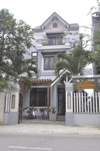 un edificio blanco con palmeras delante en Green CoCo HomeStay, en Hoi An