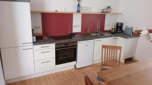 a kitchen with white cabinets and a sink and a table at Ferienhaus Hoher Vogelsberg in Herbstein
