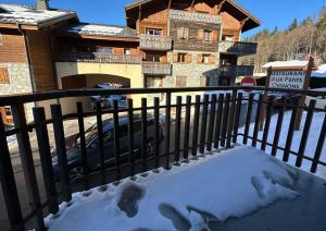 Una valla con huellas en la nieve delante de una casa en Edelweiss Résidence plein centre de la station rez de chaussée 50 m des navettes gratuites belle terrasse et grand parking privé en sous sol, en Les Carroz d'Araches