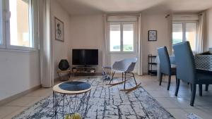 a living room with a table and chairs and a television at Apppartement 2 pièces centre-ville in Chauffailles