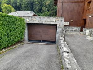 Un garaje de piedra con una puerta de garaje marrón. en Edelweiss Résidence plein centre de la station rez de chaussée 50 m des navettes gratuites belle terrasse et grand parking privé en sous sol, en Les Carroz d'Araches 1 foto más