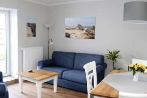 een woonkamer met een blauwe bank en een tafel bij Haus Petje in Keitum