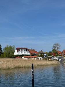 a boat in the water with houses in the background at Frisch renoviertes FH Südblick am Meer in Breege, Meerblick von allen drei Etagen, Terrasse, Balkon, Sauna und Parkplatz in Breege
