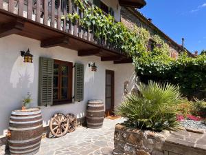a house with a porch with barrels and a balcony at Historic Wine-Stone House in Vipava