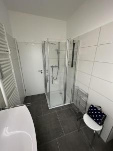 a bathroom with a shower and a chair and a glass shower stall at Leuchtturmblick in Borkum +14 photos