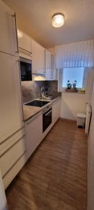a kitchen with white cabinets and a sink and a window at Kleiner Zander in Borkum