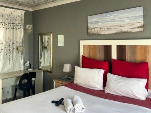 a bedroom with a bed with red and white pillows at K K K Guesthouse in Secunda