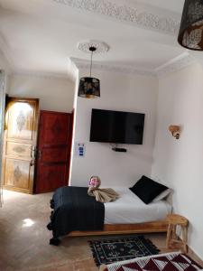 - une chambre avec un lit et une télévision murale dans l'établissement RIAD & SPA SOUS LE SOLEIL CHEZ Jérôme & Paméla, à Marrakech