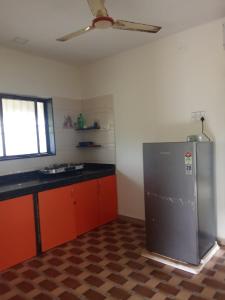 La cuisine est équipée d'un réfrigérateur en acier inoxydable et de placards orange. dans l'établissement Potdar holiday home & risort, à Chandoli