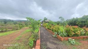 un jardin fleuri et une maison en arrière-plan dans l'établissement Potdar holiday home & risort, à Chandoli