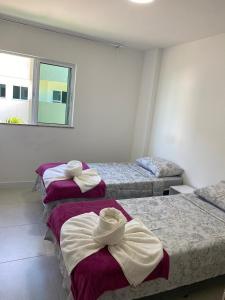 a bedroom with two beds with towels on them at Golden Lake Apart Hotel in Arraial do Cabo
