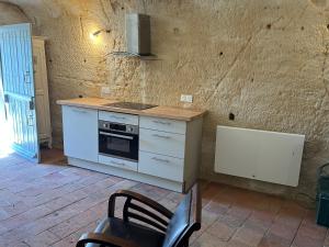 a kitchen with a stove and a counter top at Habitat troglodyte typique et confortable in Villaines-les-Rochers