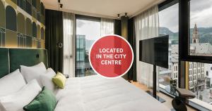 a room with a bed with a sign inscribed located in the city centre at Falkensteiner Hotel Bozen WaltherPark in Bolzano