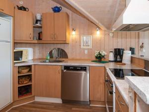 a kitchen with wooden cabinets and a sink and a dishwasher at 4 star holiday home in Hemmet in Hemmet +36 photos